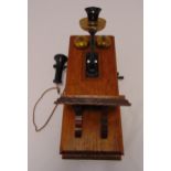 An oak mounted brass and Bakelite candlestick telephone, 51 x 22cm