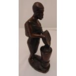 An African carved figurine of a mother carrying a baby and holding a dish on raised oval base,