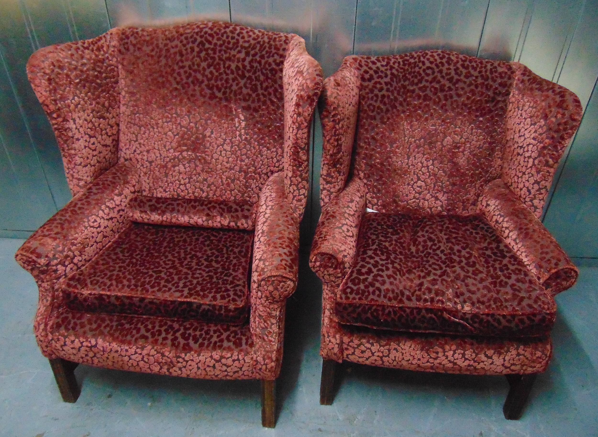 Two upholstered wing back armchairs on four tapering rectangular legs