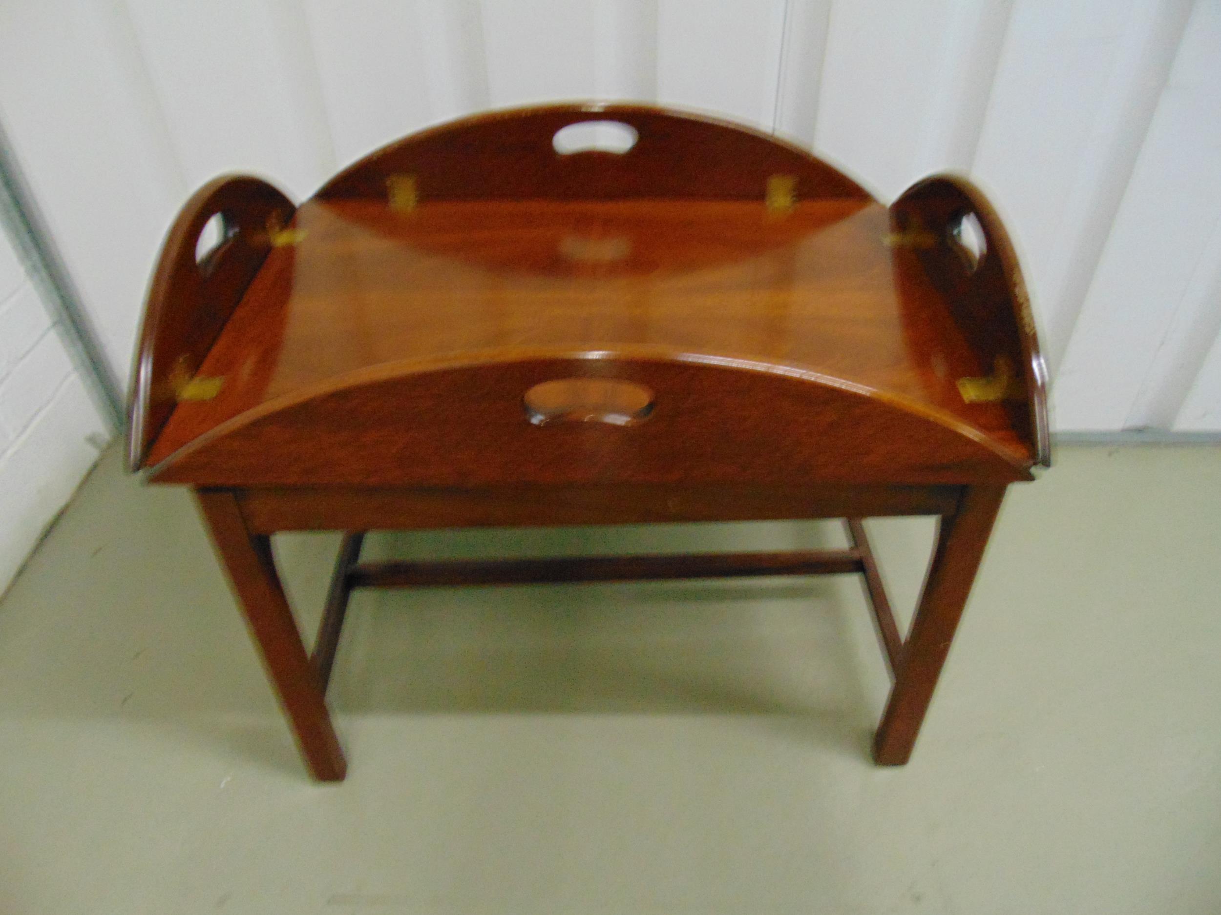 A mahogany butlers tray and stand of customary form with inset handles and brass hinges, the stand