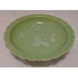 A Chinese celadon glazed bowl with scalloped border decorated with flowers and leaves, character