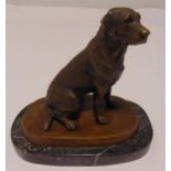 A bronze figurine of a seated dog on raised oval black marble base, 17cm (h)