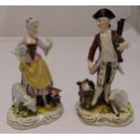 A pair of continental figurines of a shepherd and shepherdess with sheep and dogs, on shaped oval