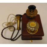 A mid 20th century brass and mahogany wall telephone with original cord and address label