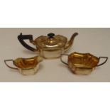 A hallmarked silver three piece tea set, shaped oval with incuse sides, Birmingham 1931 by Britton