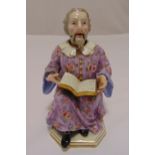 A late 19th century Meissen nodding head figure of a scholar reading a book and wearing a floral