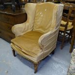 An Edwardian upholstered wing fireside armchair