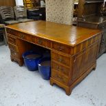 A yew wood twin pedestal writing desk, with tooled leather skiver, 10 drawers, on bracket feet,