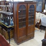 A 1920s oak bookcase with arch-top glazed panelled cupboard doors, with drawer under, on bun feet,