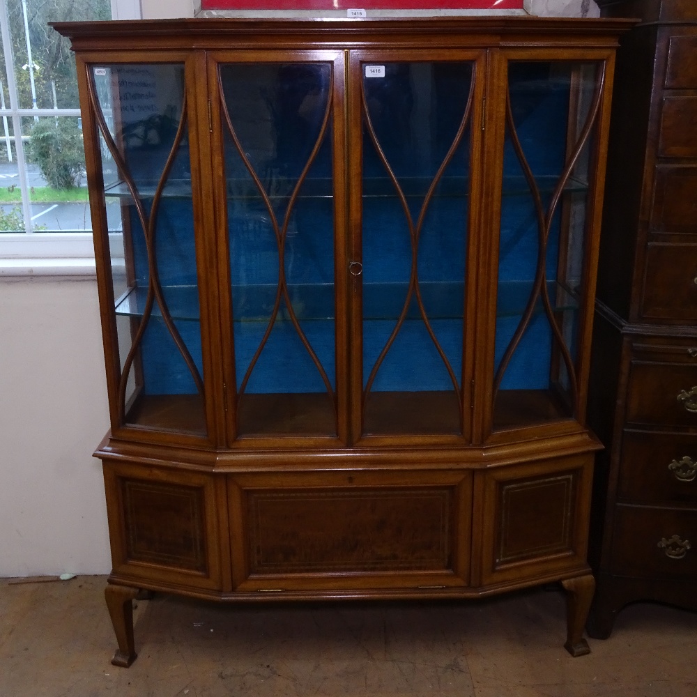 An Edwardian mahogany and satinwood-banded display cabinet of canted form, with lattice-glazed doors