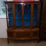 An Edwardian mahogany and satinwood-banded display cabinet of canted form, with lattice-glazed doors