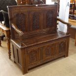 An Antique oak settle, with carved floral arched panels, rising seat, on stile legs, W124cm, H122cm,