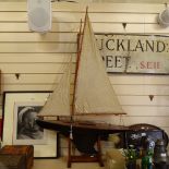 A 19th century black lacquered wooden-hulled model pond yacht, with sails and rigging, hull