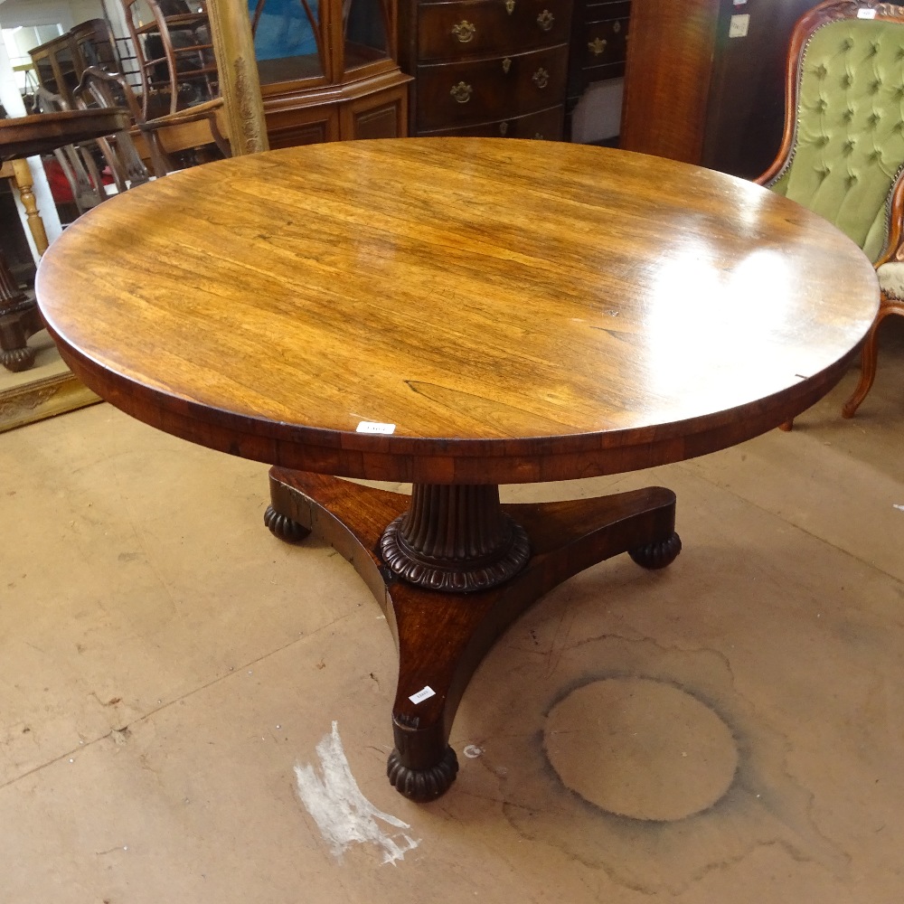 A Regency rosewood circular tilt-top breakfast table, on a reeded fluted column and trefoil base, on