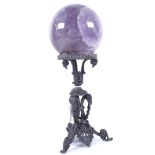 A large polished amethyst sphere crystal ball, on a spelter ram's-head stand, overall height 31cm