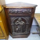 An Antique oak corner cupboard, with a figural relief carved panelled door, H105cm