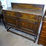A 1920s oak sideboard with drawer and cupboards, applied carved decoration, on baluster legs,