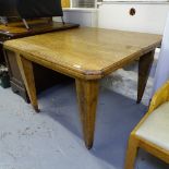 A 1920s oak canted corner wind-out dining table, with single spare leaf