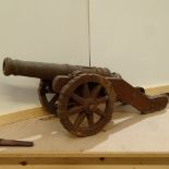 A small scale heavy weathered cast-iron garden signal cannon, on cast-iron wheeled carriage, overall