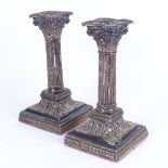 A pair of silver plated Corinthian column squat table candlesticks, relief embossed decoration, with