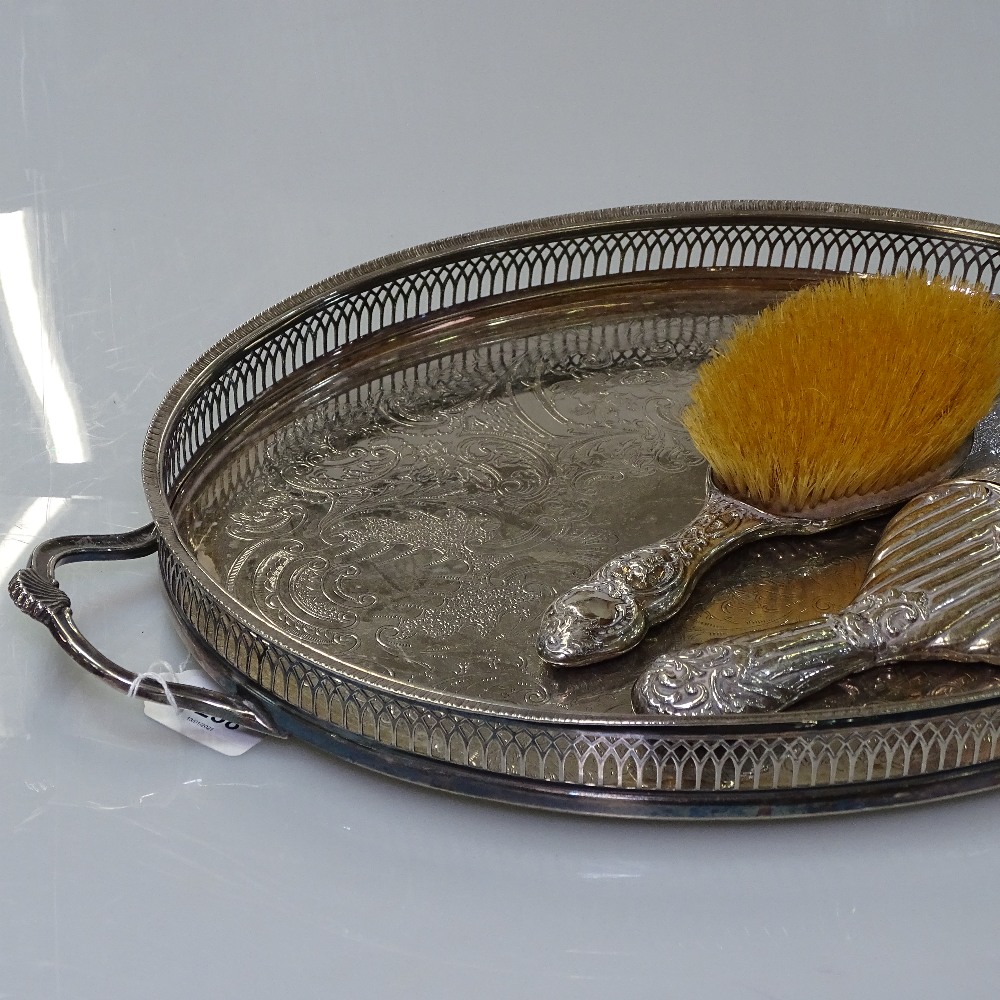 An Art Nouveau silver-backed embossed dressing table brush, a silver-backed table mirror, and a