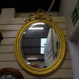 A large early 20th century giltwood oval bevel-edge wall mirror, with ribbon pediment, overall