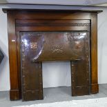 An Arts and Crafts oak and copper fire surround, with hammered roundels and embossed lion