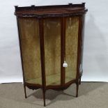 An Edwardian mahogany serpentine-front display cabinet, with carved friezes and serpentine glass