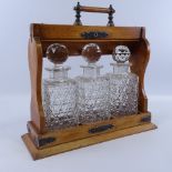 A Victorian oak 3-bottle tantalus, with electroplate mounts and glass decanters, length 32cm (A/F)