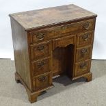 A Georgian walnut kneehole desk of small size, quarter veneered and feather-banded top, with drawers