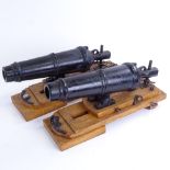 A pair of cast-iron barrelled model cannons on stained oak stands, overall barrel length 28cm,