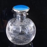 An Edwardian cut glass perfume bottle, with silver and blue enamel top, height 10cm. Lid hinge is
