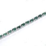 A modern 14ct white gold emerald and diamond tennis line bracelet, set with oval mixed-cut