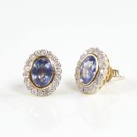 A modern pair of 14ct gold sapphire and diamond cluster stud earrings, set with oval-cut sapphires