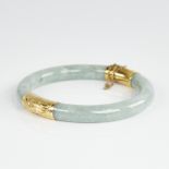 A Chinese polished jade hinged bangle, with engraved 14ct gold mounts, band width 8.2mm, internal
