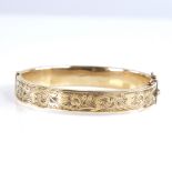 A mid-20th century 9ct gold hinged bangle, engraved foliate decoration, hallmarks Birmingham 1961,