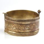 A 19th century unmarked silver? gilt hinged bangle, engraved floral panels, band width 32.7mm,