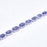 A modern platinum tanzanite and diamond cluster line bracelet, set with graduated panels of oval-cut