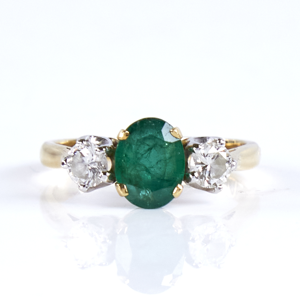 A mid-20th century unmarked high carat gold 3-stone emerald and diamond ring, set with oval mixed-