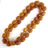 A long graduated single row butterscotch amber barrel bead necklace, beads measuring from 26.5mm