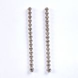 A pair of unmarked white gold graduated diamond line pendant earrings, total estimated diamond