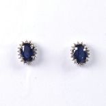 A modern pair of 14ct white gold sapphire and diamond cluster stud earrings, set with oval mixed-cut
