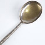 A large Indian unmarked white metal serving spoon, relief embossed foliate handle, length 26cm, 1.