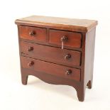 A miniature stained pine apprentice piece table-top chest of drawers, height 23cm, width 24cm