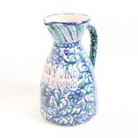 A Spanish faience glazed pottery wine jug, with allover painted decoration and inscription "con