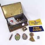 Various military badges, arm bands in a biscuit tin