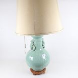 An Oriental celadon style table lamp on wooden plinth, with shade, height 82cm overall