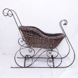 A wicker sled on scrolled wrought-iron base