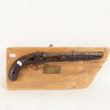 A heavily weathered 18th century percussion pistol, mounted on driftwood board with plaque "Found in