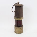 A brass miner's lamp with cranberry glass shade, height 27cm
